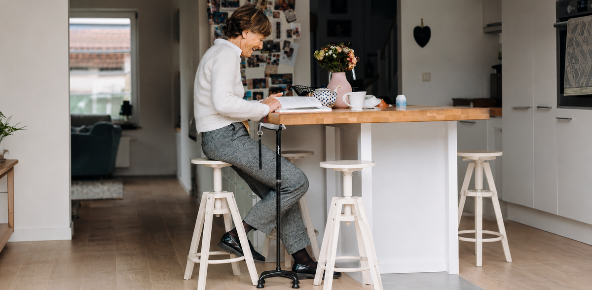 Woman seated at a kitchen counter with a self-standing cane